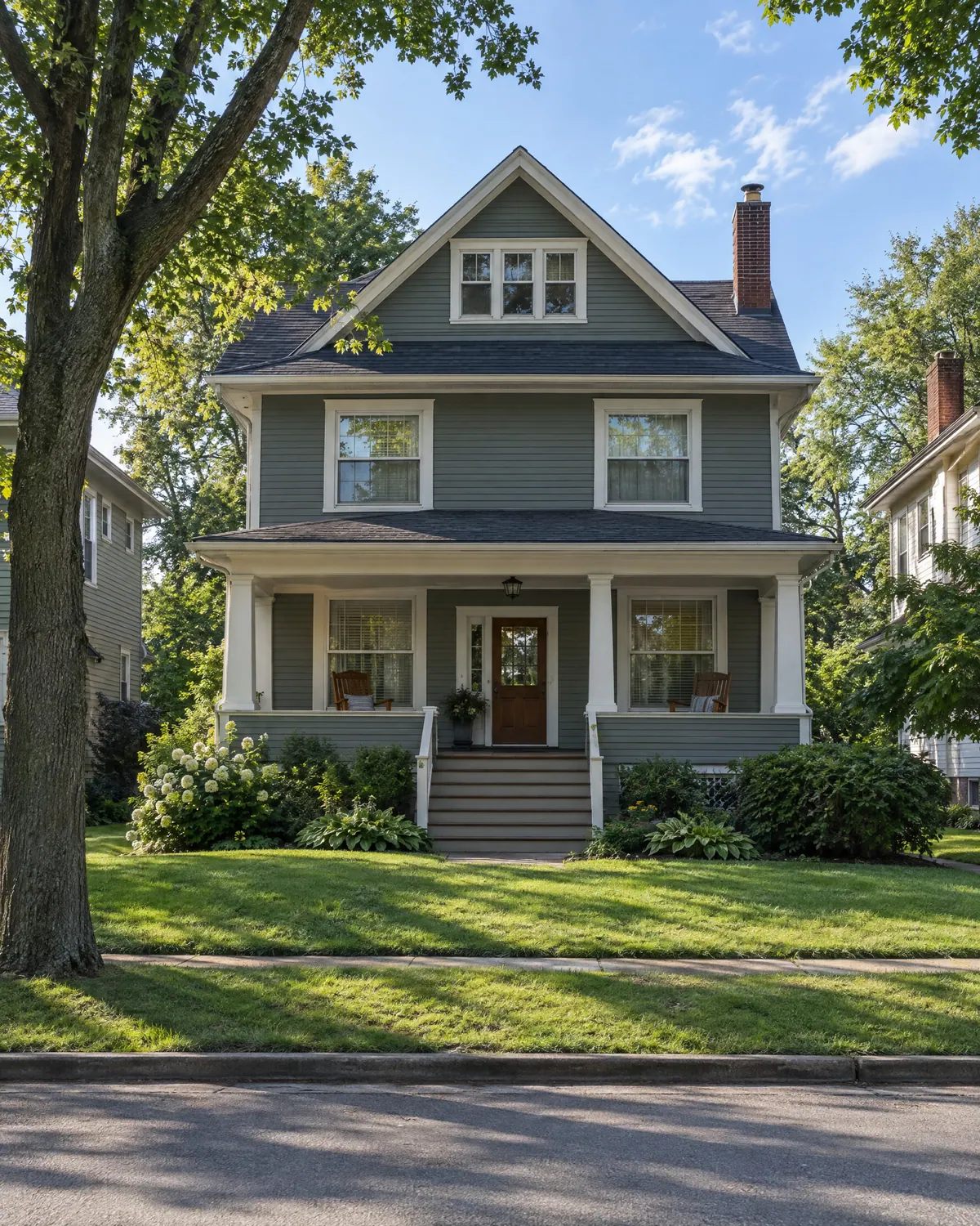 Gray foursquare house with a deep front porch on a sunny summer morning
