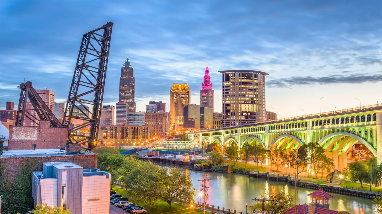 Downtown Cleveland at dusk above the Cuyahoga River in the Flats, with an arched bridge lit green