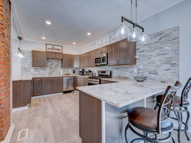 Kitchen with dark wood cabinets, a granite breakfast bar with stools and a brick chimney