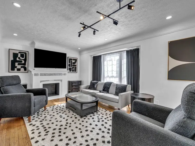 Living room with a fireplace, gray sofas and a spotted rug on hardwood
