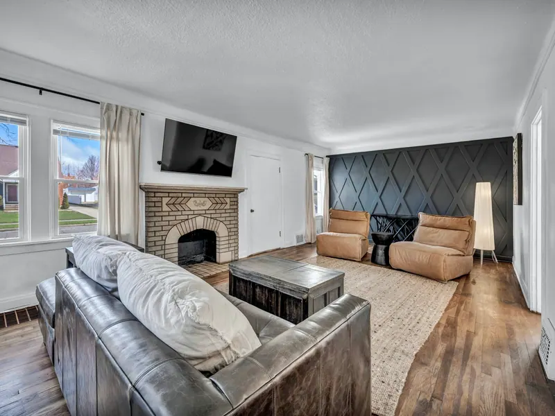 Living room with a brick fireplace, leather sofa and a paneled accent wall