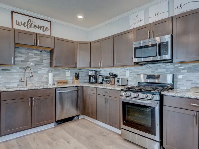 Kitchen with wood cabinets, a stone tile backsplash and a gas range