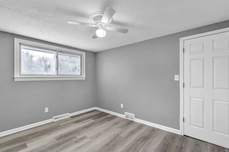 Bedroom with a window on one wall and the door on the other