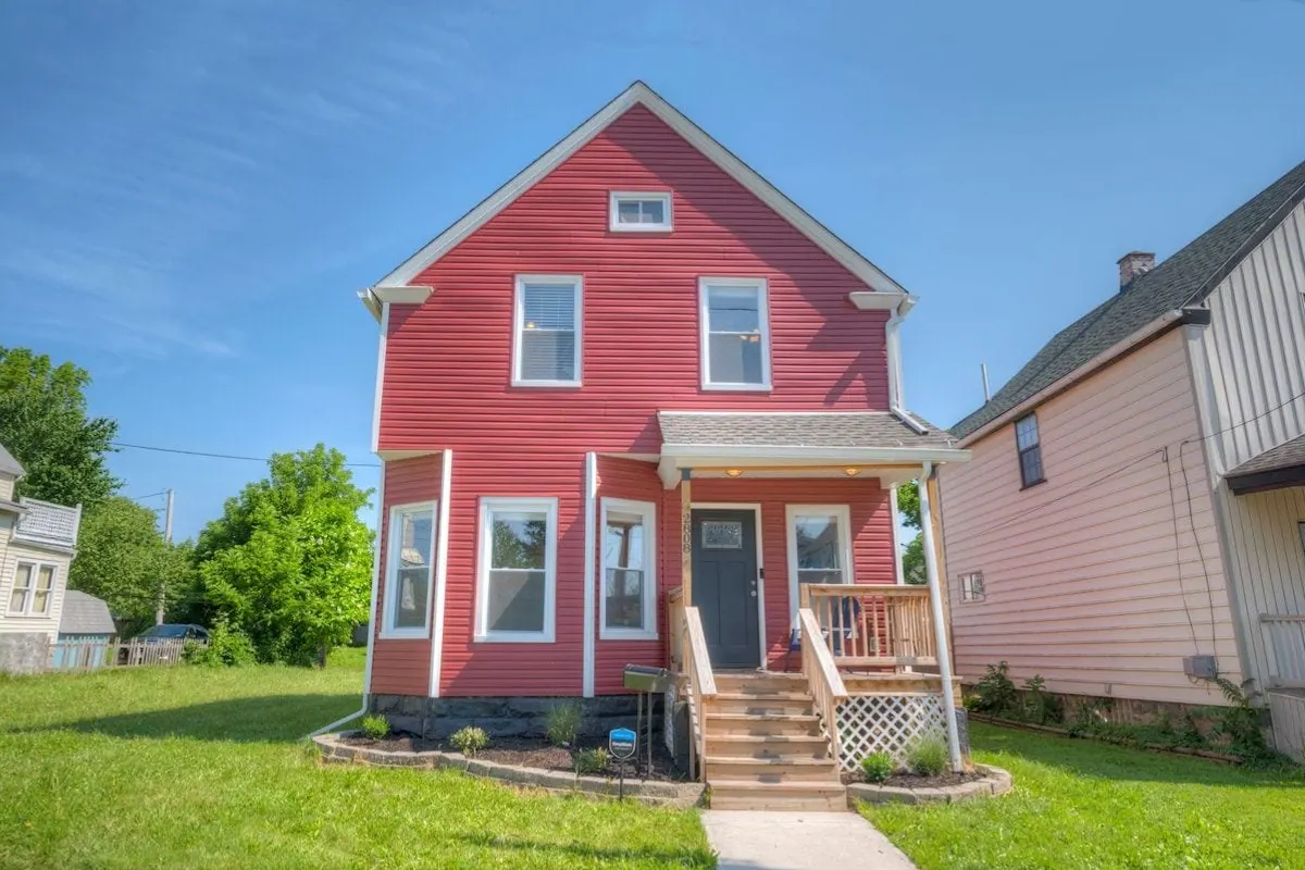 Red two story house with a covered front porch and wooden steps
