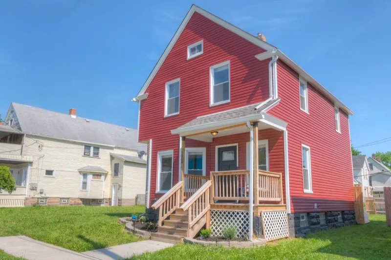 Side view of the red house showing the porch and the neighboring street