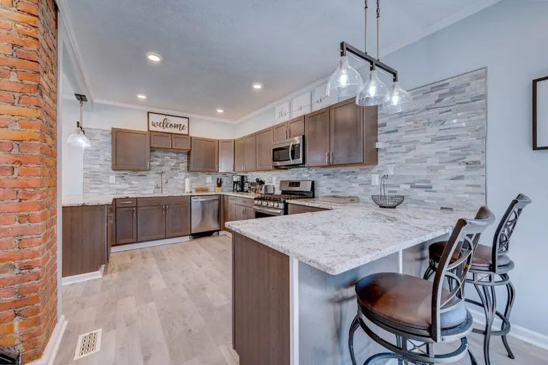 Kitchen with dark wood cabinets, a granite breakfast bar with stools and a brick chimney