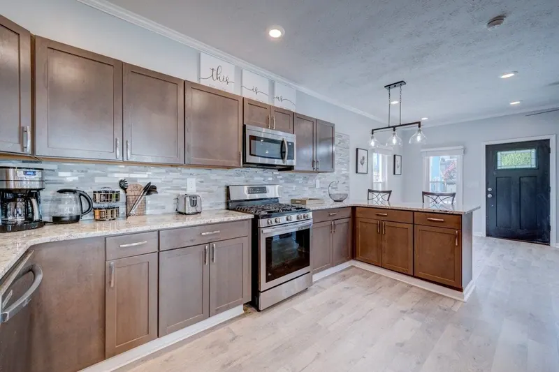 Kitchen from the dining side, with a gas range, microwave and the front door beyond
