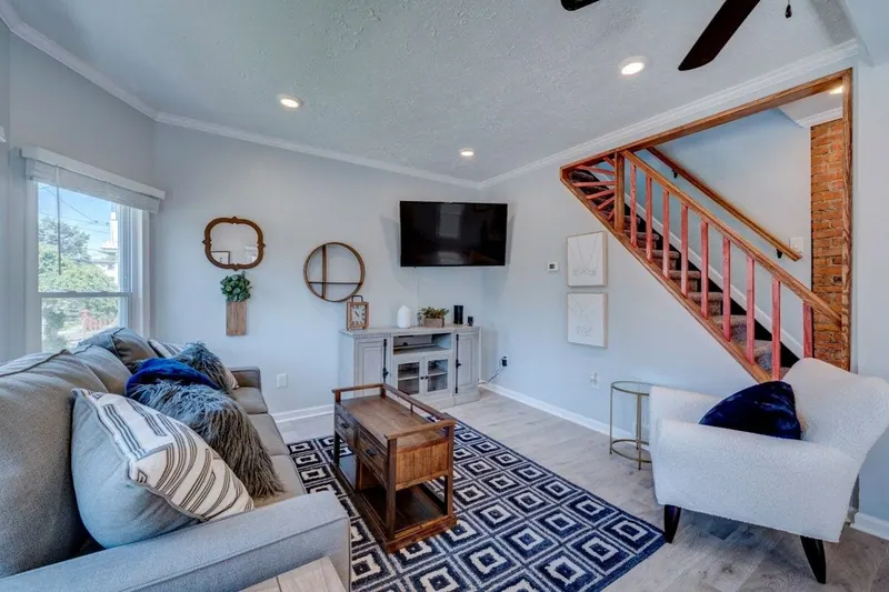 Living room with a wall mounted television and a staircase with a wood rail