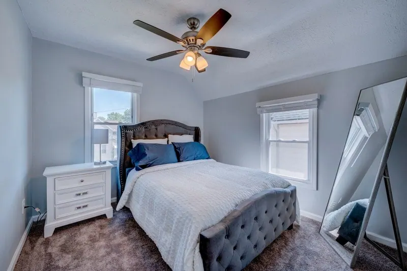 Bedroom with a queen bed, tufted headboard and a tall leaning mirror