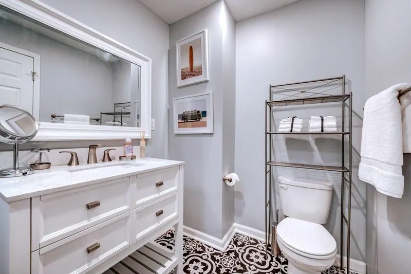 Bathroom with a white vanity, framed mirror and patterned tile floor