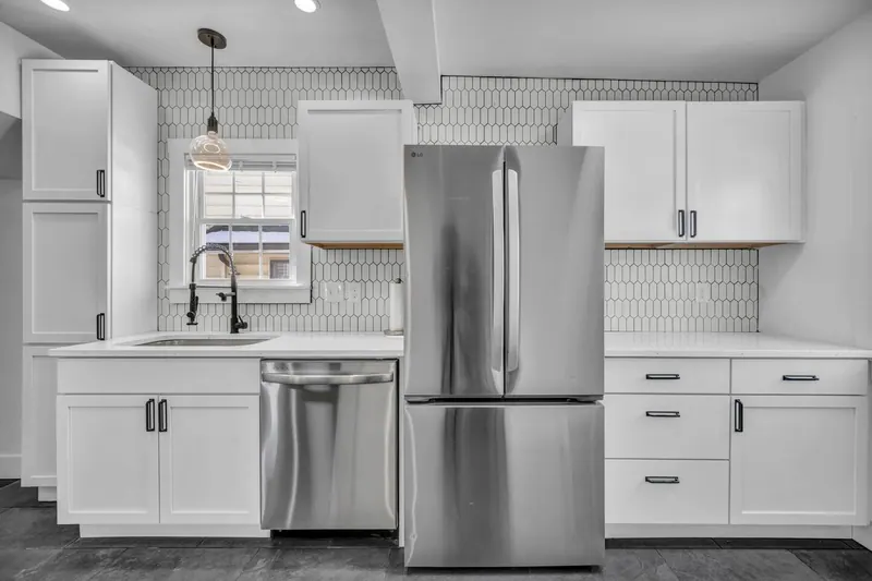 Kitchen with a stainless dishwasher and refrigerator under pendant lighting