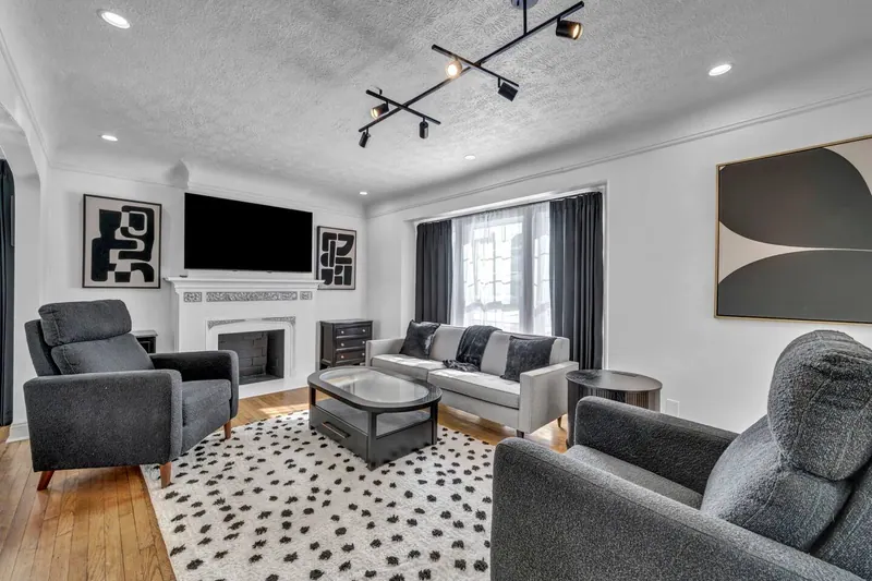 Living room with a fireplace, gray sofas and a spotted rug on hardwood