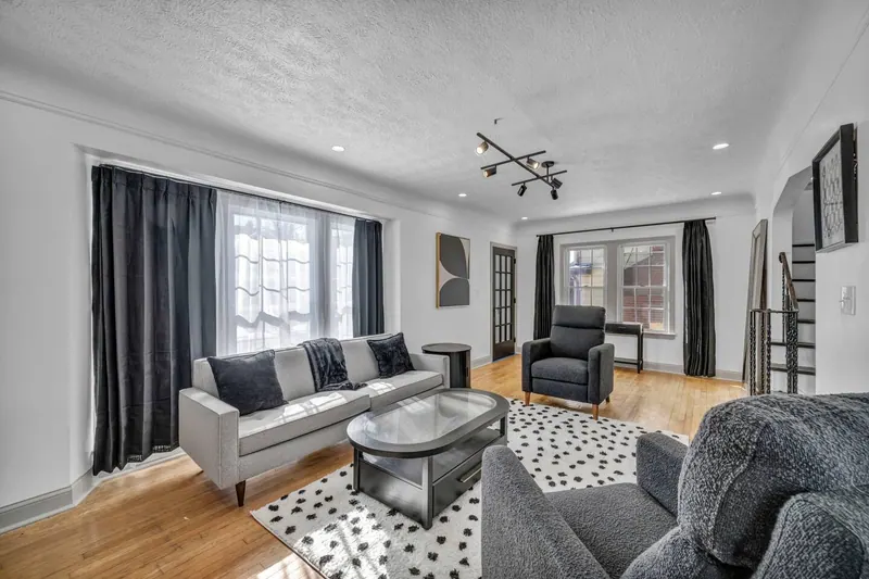 Living room from the far side, with tall curtained windows and a low sofa