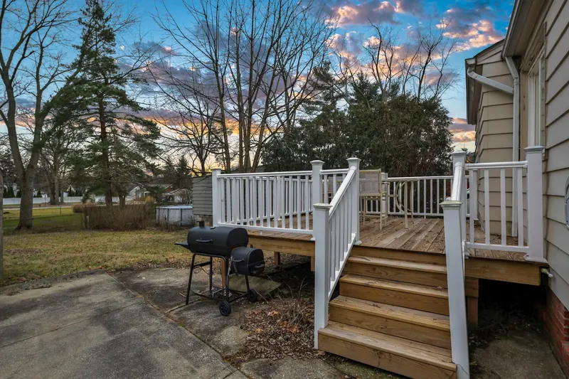 Deck steps down to the yard, with a charcoal grill beside them