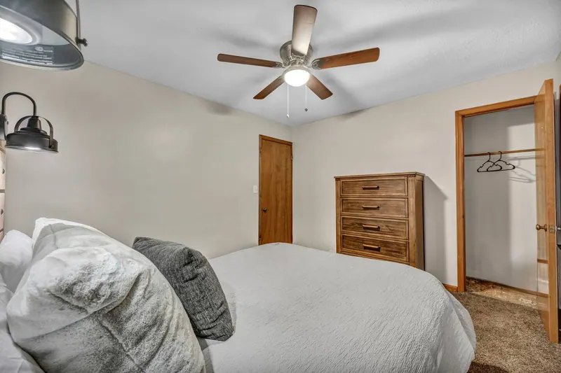 Bedroom with a queen bed, a wooden dresser and a ceiling fan