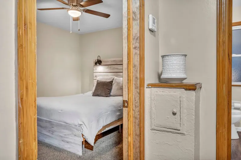 Bedroom seen from the doorway, with a queen bed against the window wall