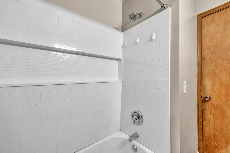 Bathroom with a white subway tiled tub and shower