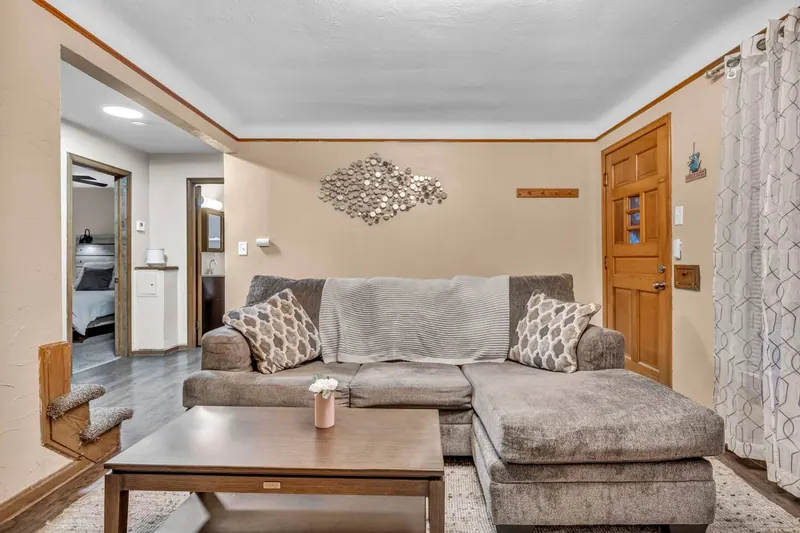 Living room with a gray sectional, a wall mounted television and a wood front door