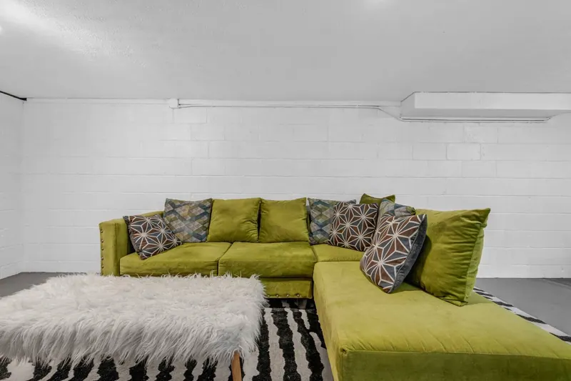 Finished basement with a green sectional and a striped rug
