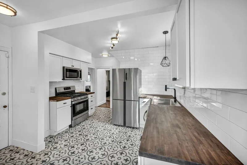 Kitchen with white cabinets, butcher block counters and a patterned tile floor
