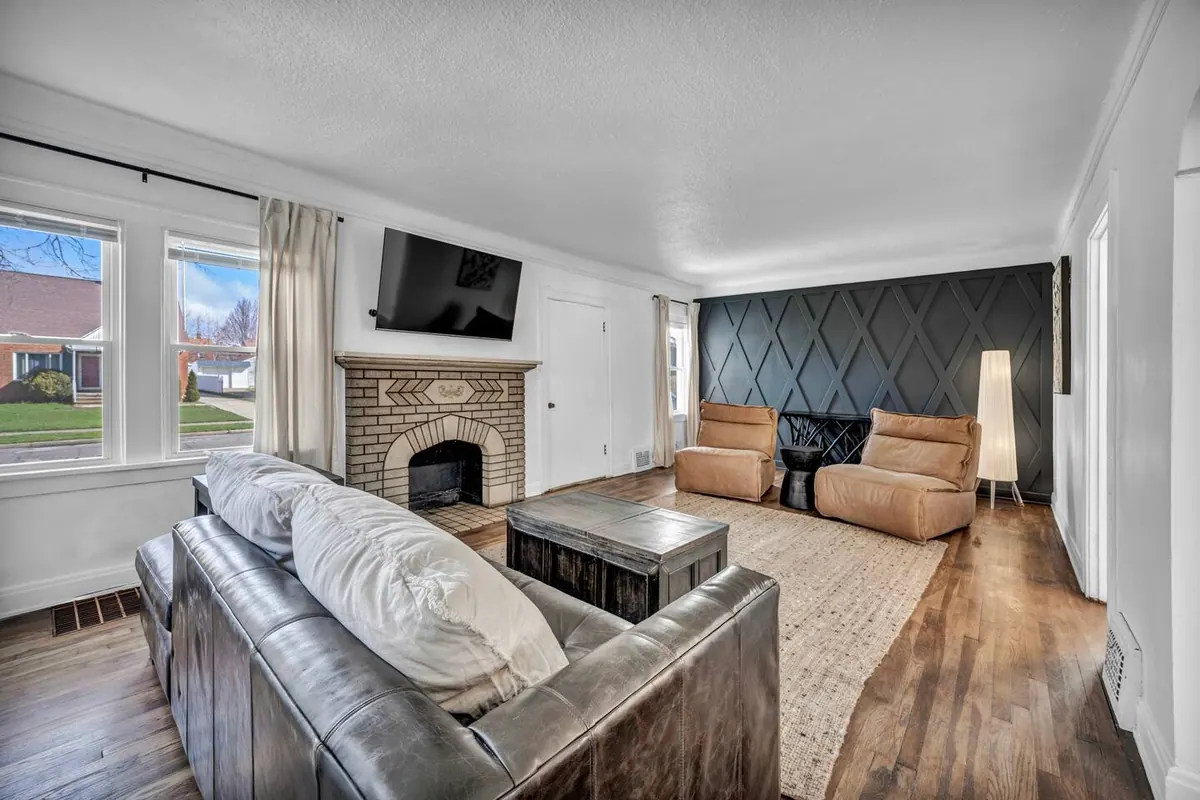 Living room with a brick fireplace, a leather sofa and a panelled navy accent wall