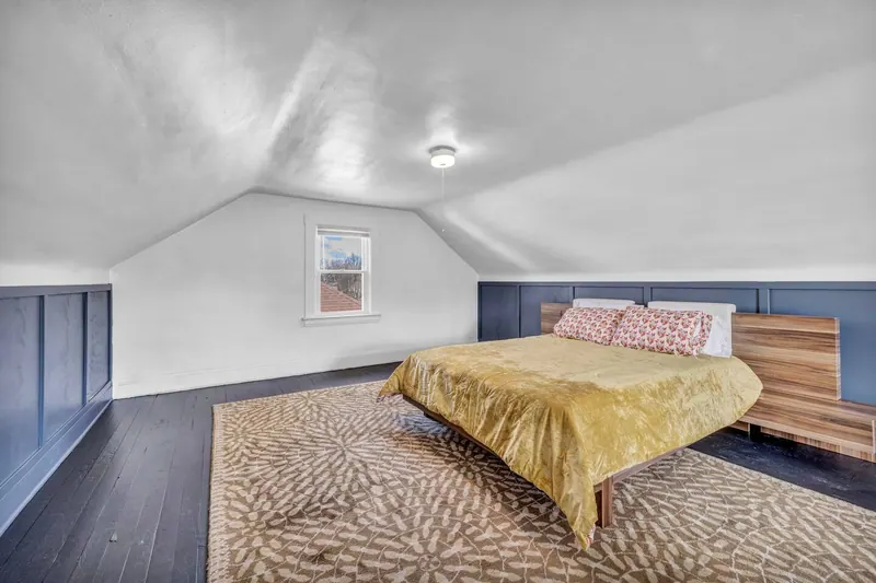 Top floor bedroom from the doorway, with a patterned rug across the boards