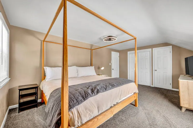 Bedroom with a wooden four poster bed and a television opposite
