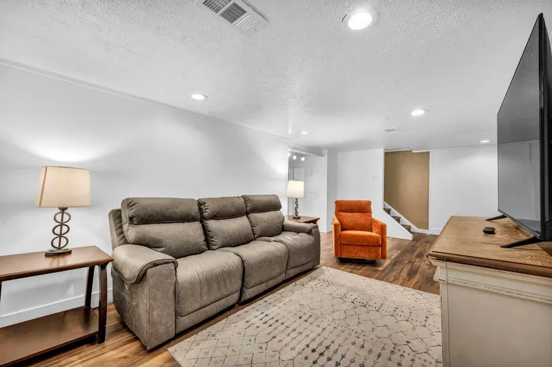 Finished basement with a sofa, an armchair and a television